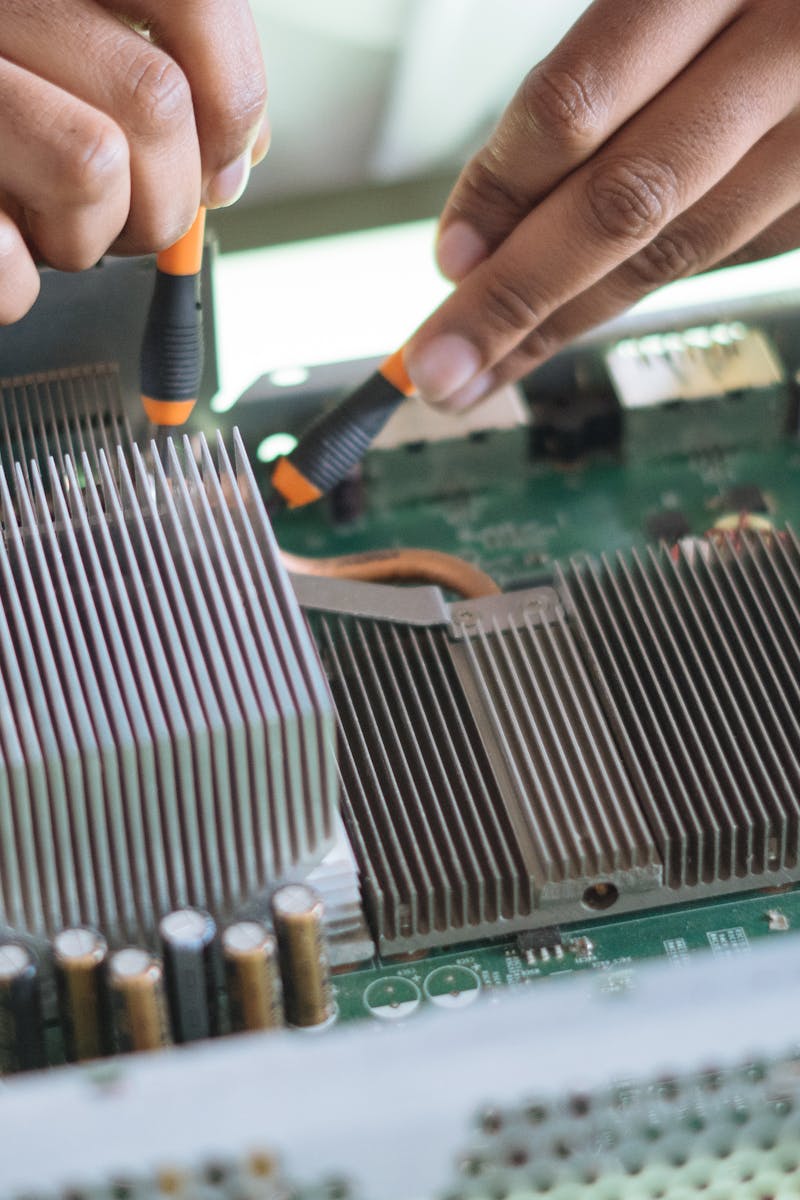 Close-up of a technician repairing a computer motherboard, focusing on microprocessor and heat sink.